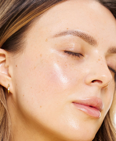 Close-up of a woman with her eyes closed, highlighting smooth, radiant skin and a natural complexion.